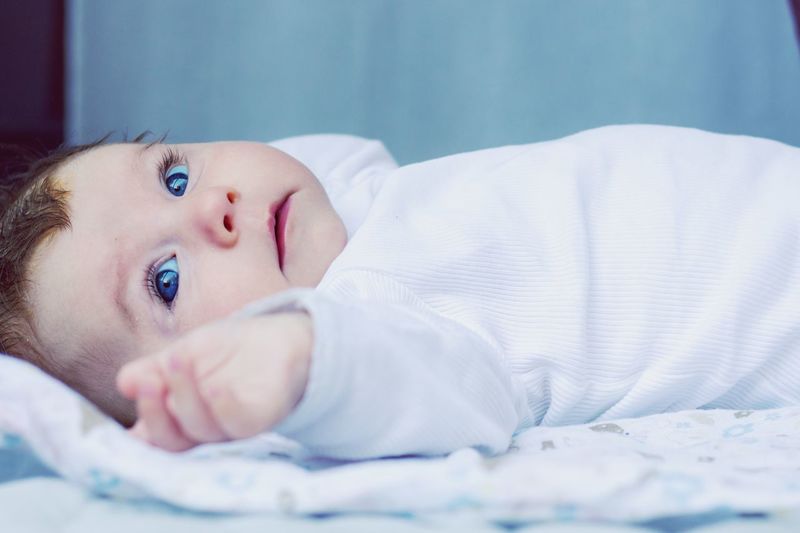 Cute toddler looking away while lying on bed