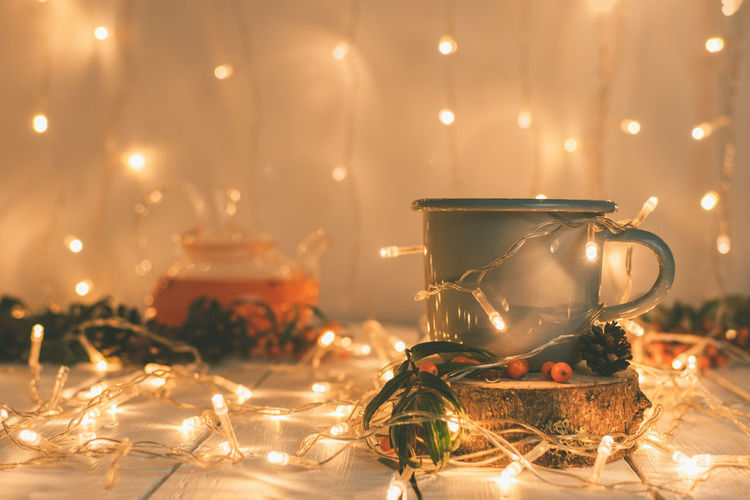 Christmas composition in warm colors from a cup of sea buckthorn tea, a teapot and a festive garland