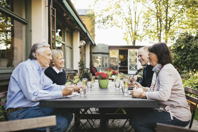 Side view of happy senior couples having food at outdoor restaurant