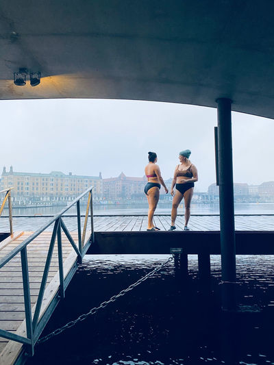 Two women standing on wooden dock before cold water swim south denmark