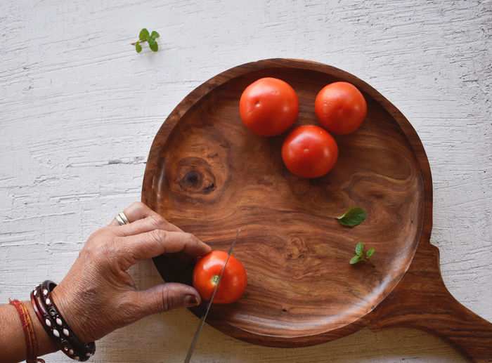 High angle view of hand holding tomatoes on table