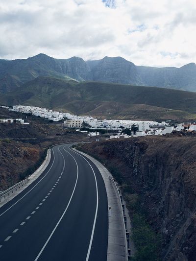 Scenic view of road by mountains against sky