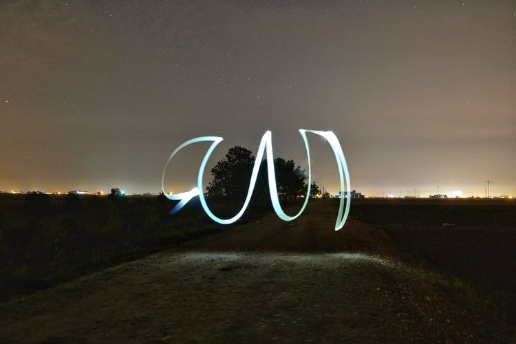 Light painting over dirt road against sky at night