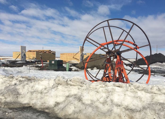 Ferris wheel on snow covered land against sky