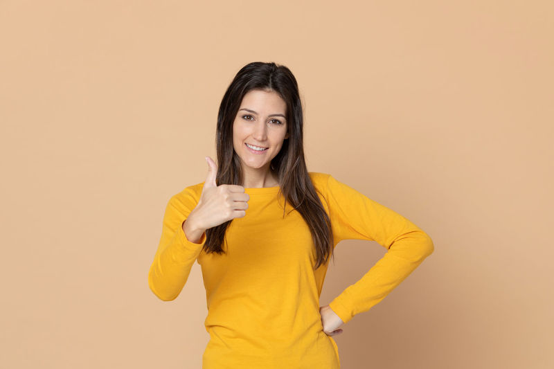 Portrait of a smiling young woman against yellow background