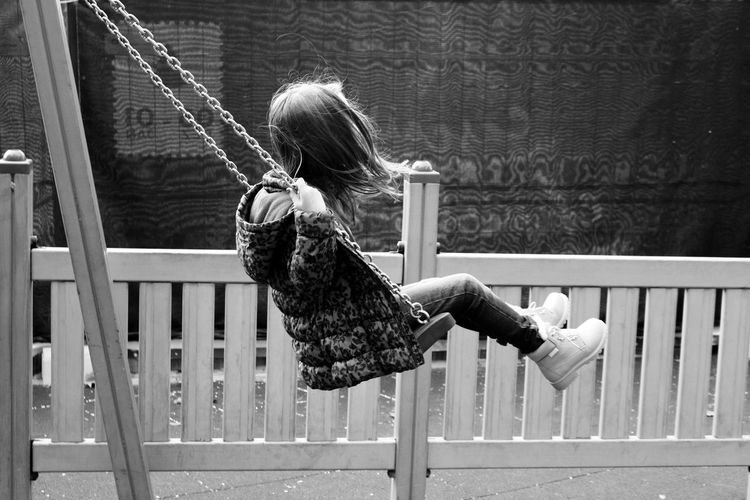 Side view of girl enjoying swing at playground