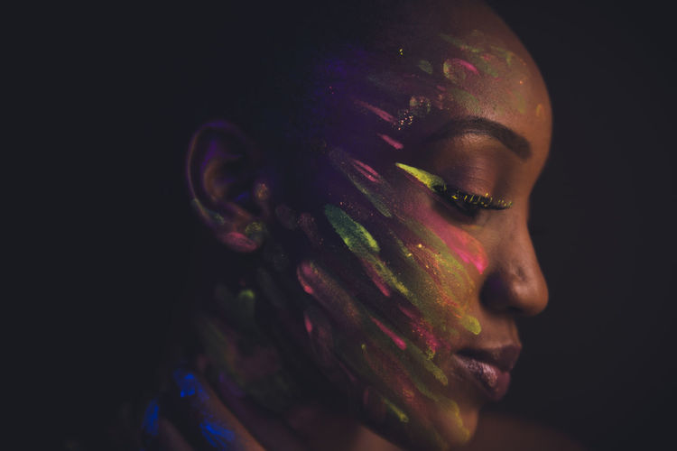 Close-up woman with powder paint on face against black background