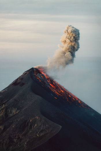 View of smoke emitting from volcanic mountain against sky