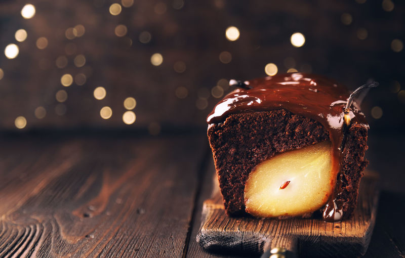 Chocolate cake with pear at rustic wooden background with bokeh. christmas brownie with fudge. 
