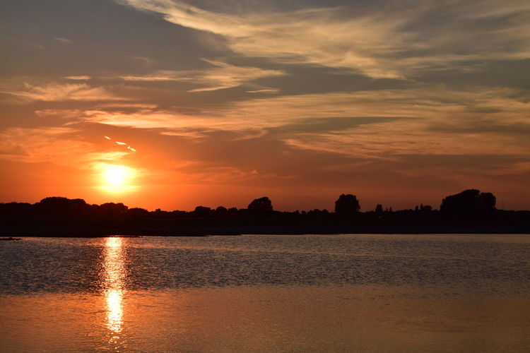 Scenic view of river against orange sky