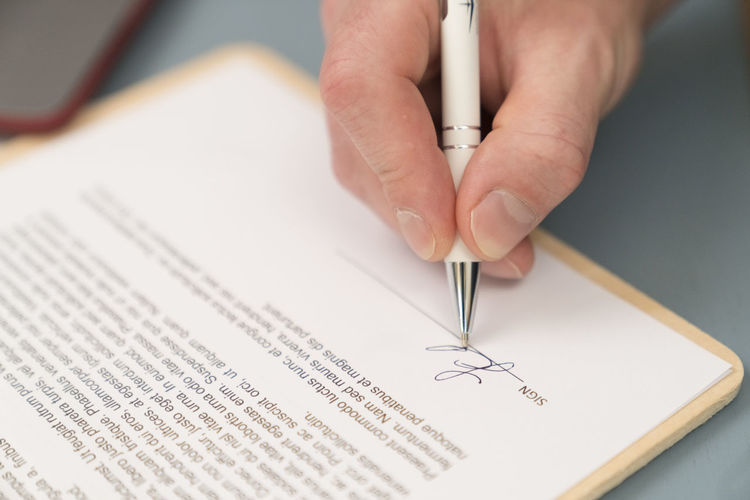 Close-up of businessman giving signature on contract paper at home