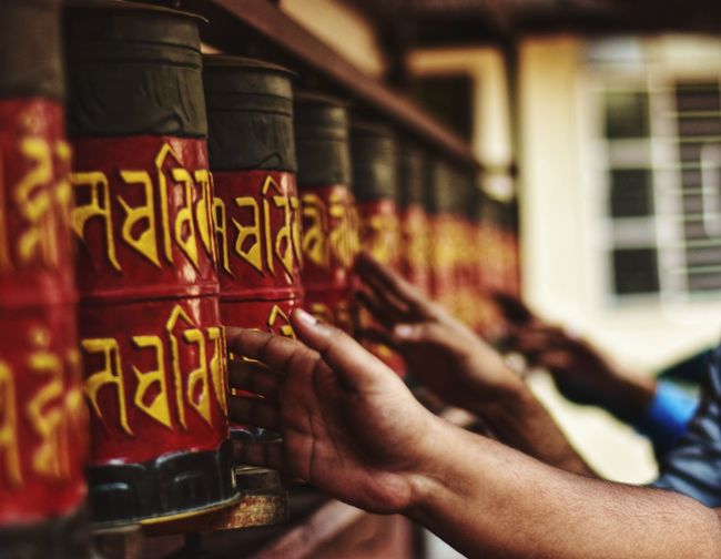 Midsection of people holding prayer wheels temple