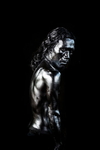 Side view of shirtless man against black background