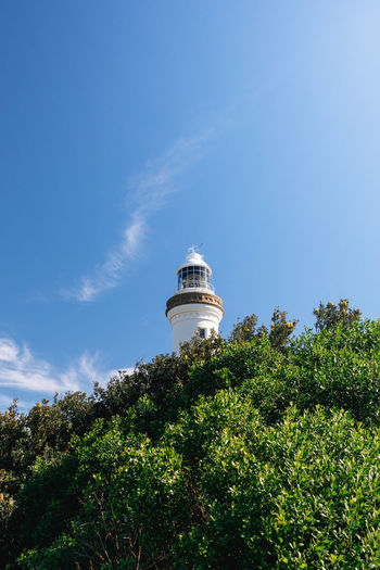 Low angle view of lighthouse by tree and building against sky