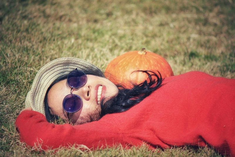 Portrait of woman wearing sunglasses while lying on grassy field