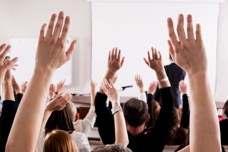 People with arms raised in lecture hall during seminar