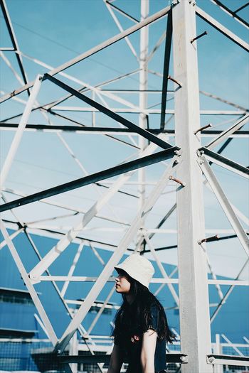 Side view of woman looking away by metal structure