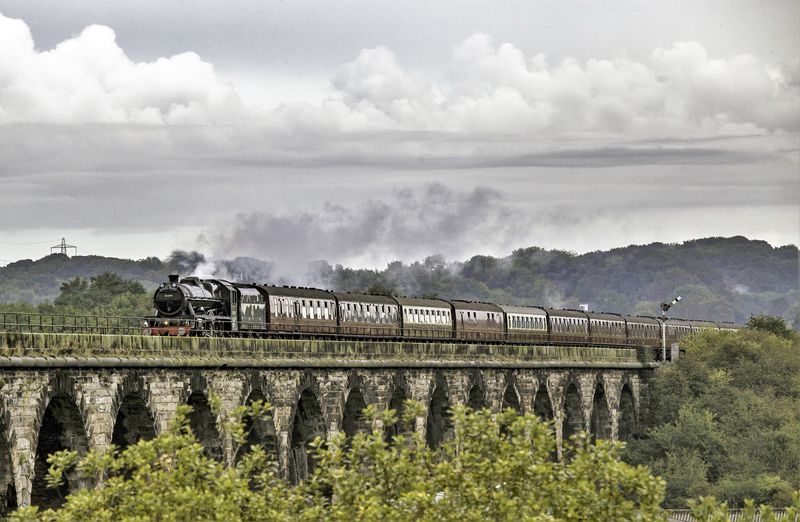Steam train on railroad viaduct against sky