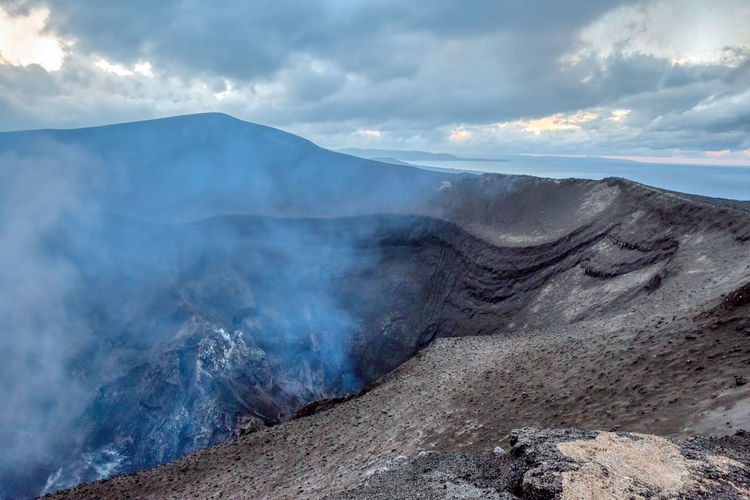 Smoke emitting from volcanic mountain against sky