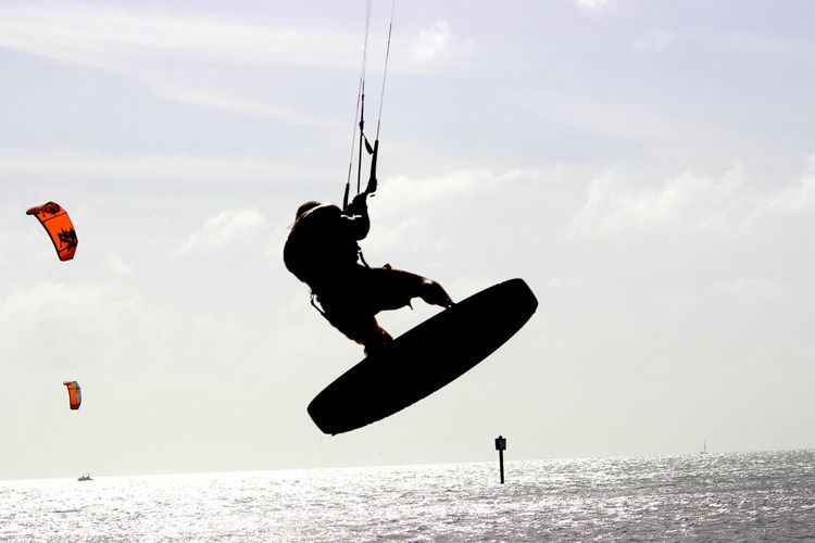 Rear view of man windsurfing in sea against sky