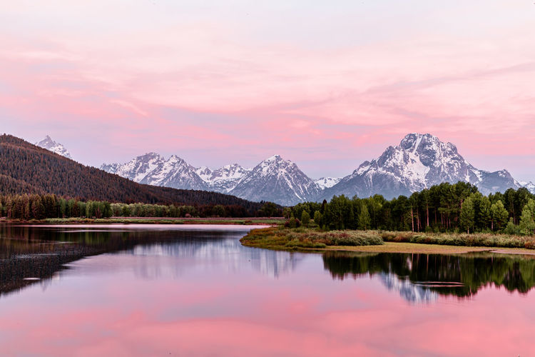 Scenic view of lake by mountains against sky during sunset