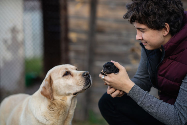 Side view of man with dog. young man holding a little puppy of labrador in his hands