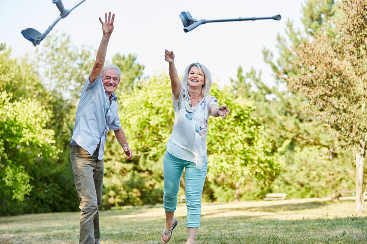 Happy couple throwing crutches in park