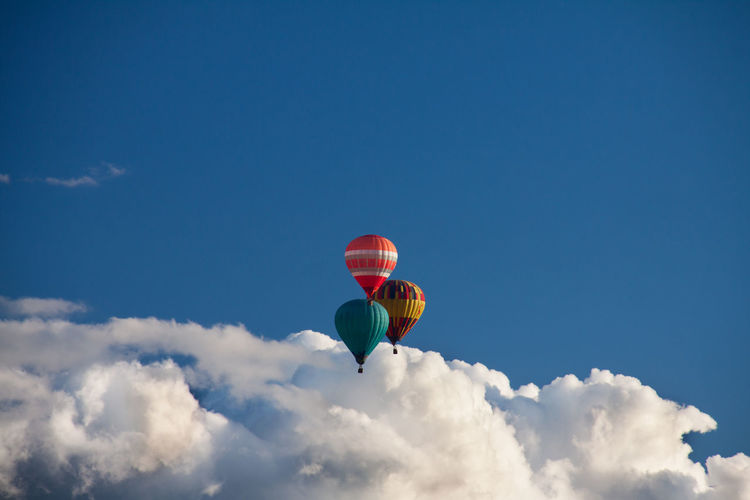 Low angle view of hot air balloons flying in blue sky