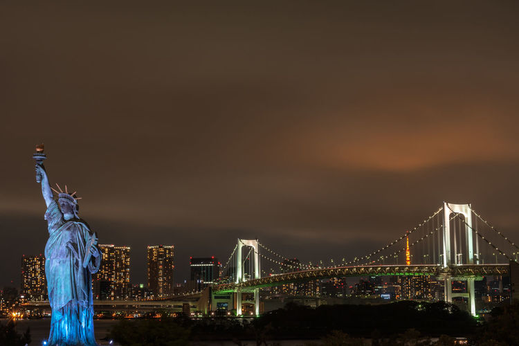 Illuminated statue of bridge in city against sky