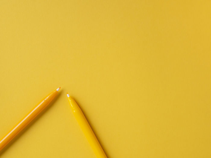 High angle view of pencils on yellow background