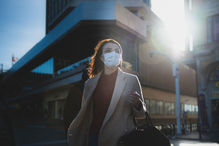 Woman wearing mask on road against buildings