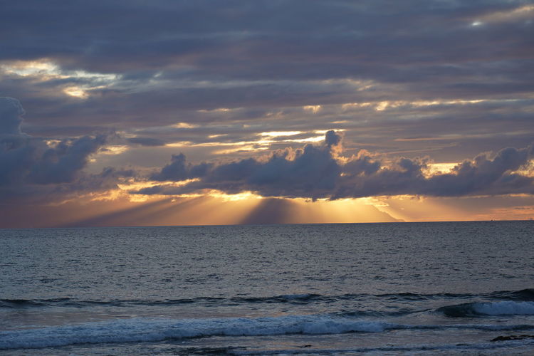 Spectacular sunset behind clouds over island la gomera, seen from playa de las américas, tenerife
