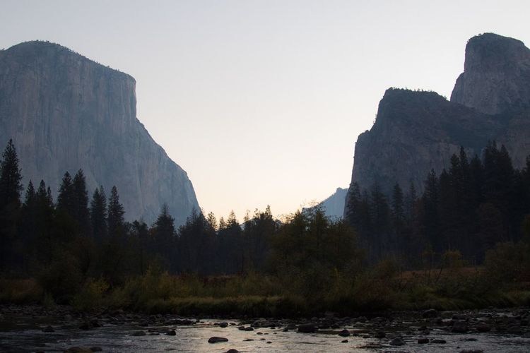 Scenic view of river by mountains against clear sky