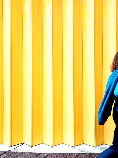 Low section of woman standing against yellow wall