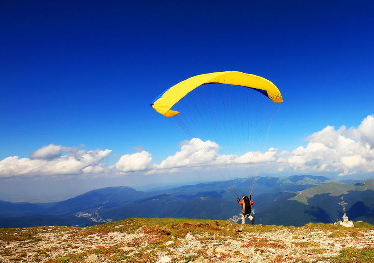 Rear view of person paragliding on carpathian mountains