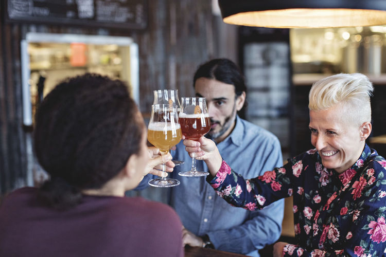 Multi-ethnic friends toasting glasses while sitting at bar