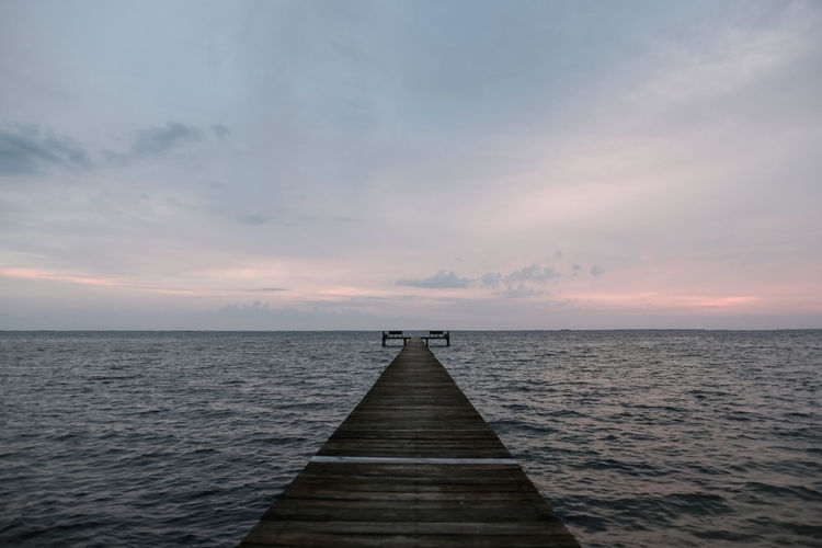Pier over sea against sky during sunset