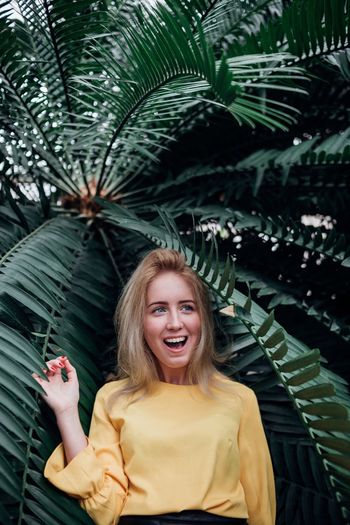 Surprised woman standing against palm tree