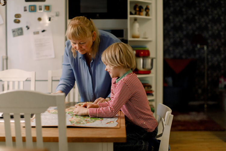 Senior woman playing board game with grandson at table