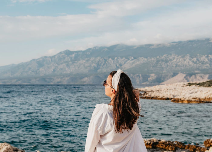 Woman looking at sea against mountain