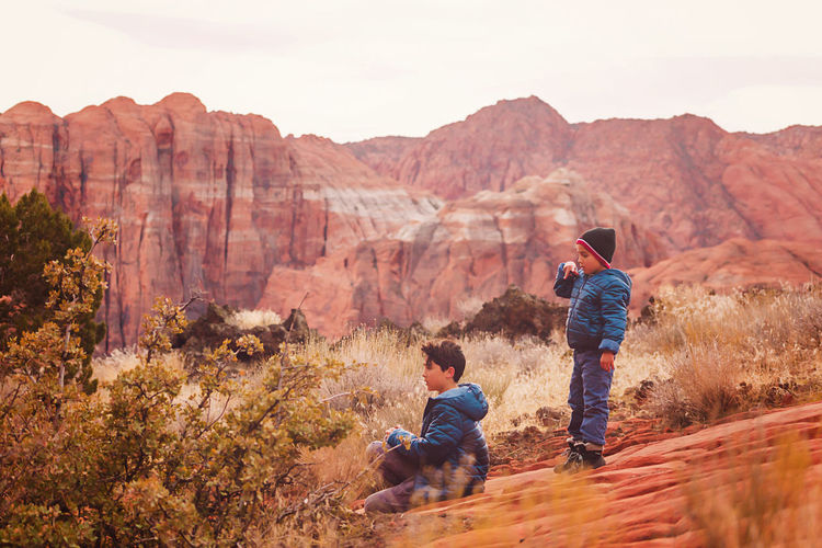 Two boys playing on trail by the red sandstone cliffs and mountains