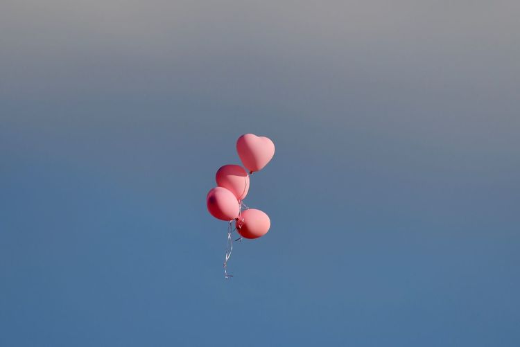 Red balloons flying against sky