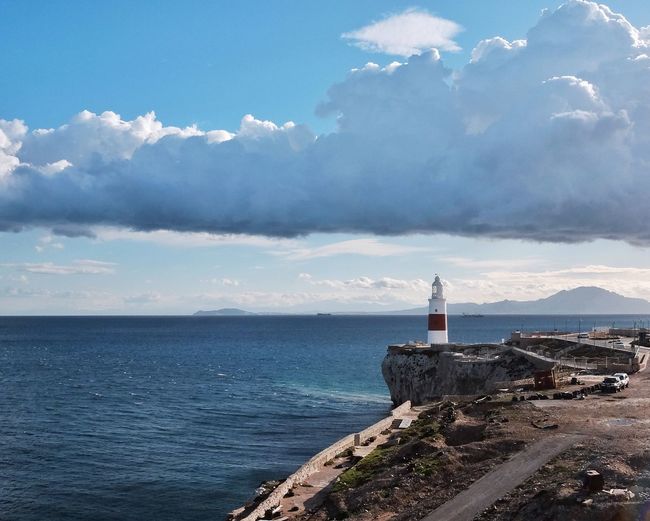 Lighthouse by sea against sky