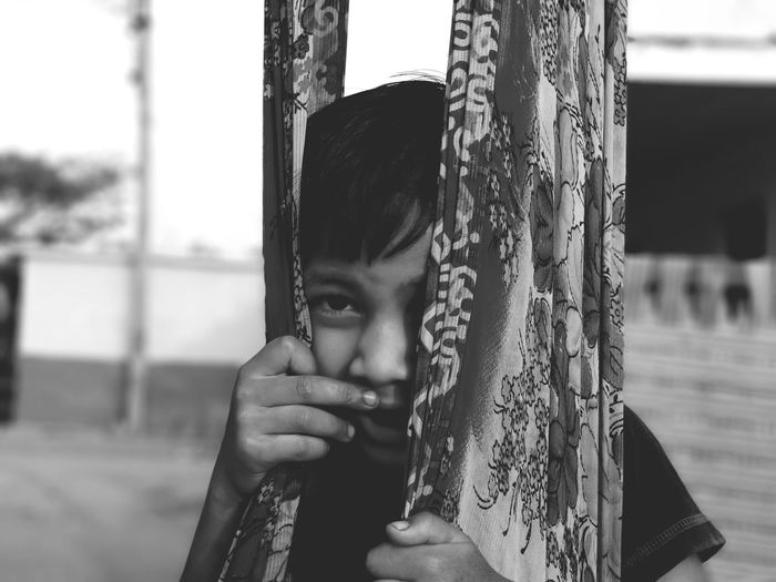 Portrait of a boy hiding face outdoors