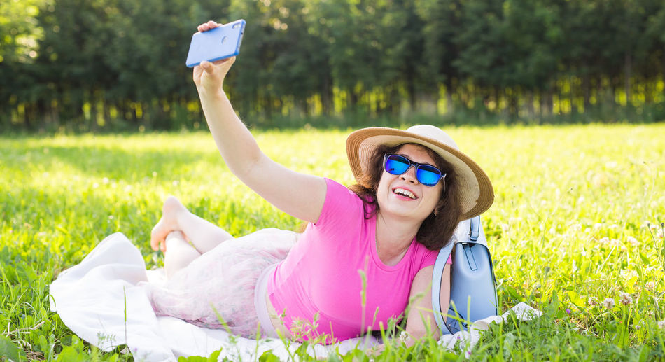 Beautiful woman doing selfie while lying on grass at park