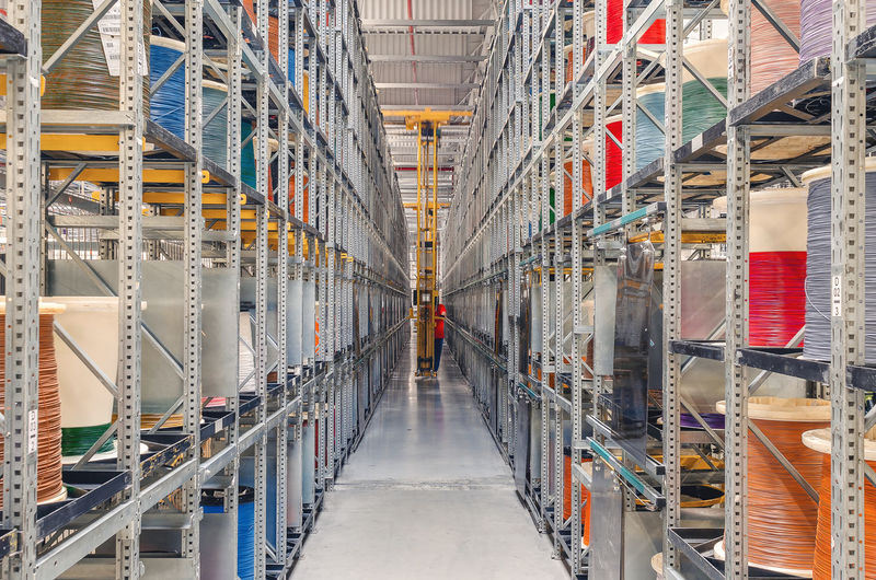 Interior of modern storage warehouse with coils of colored cable on metal shelves. forklift lift 