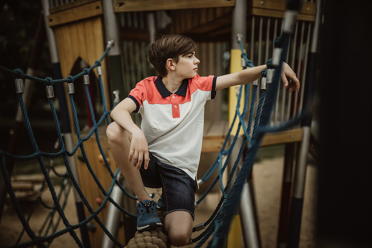 Full length of boy crouching on jungle gym