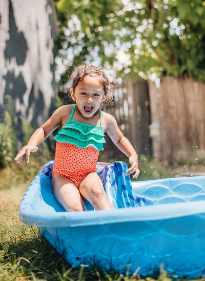 Cute smiling girl sitting in wading pool outdoors