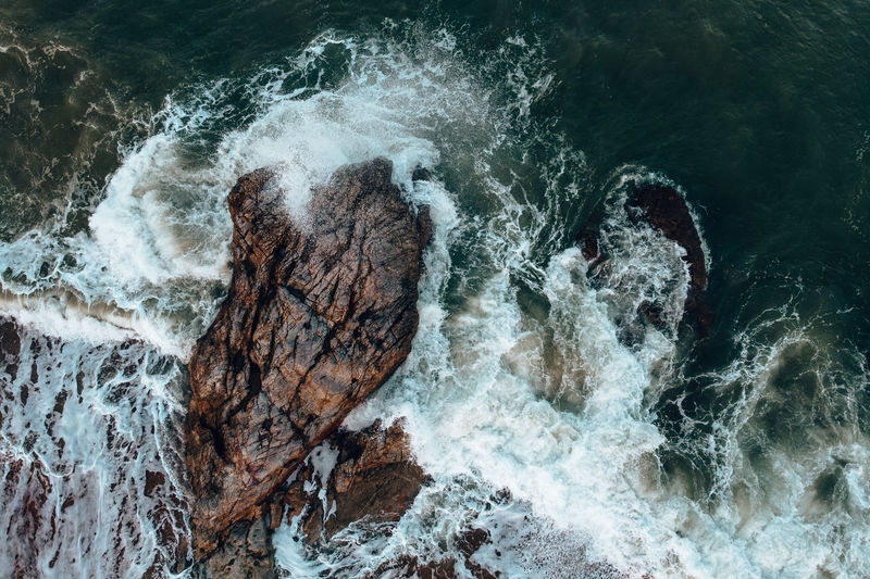High angle view of wave splashing on rock