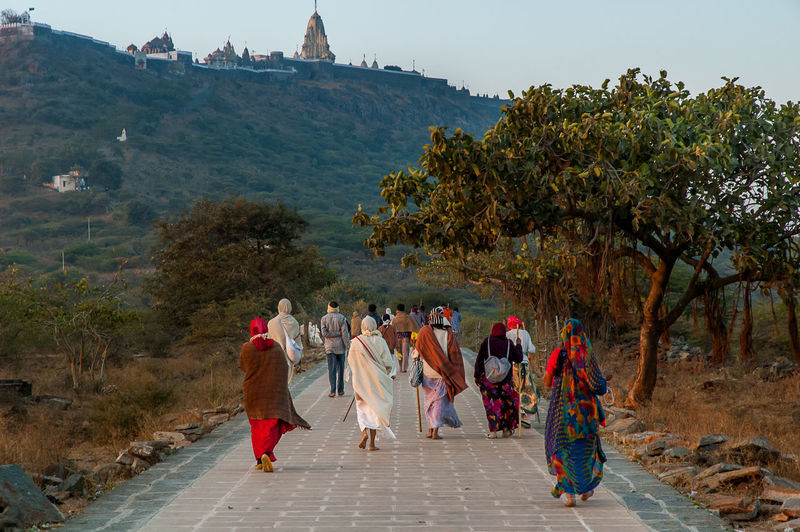 People walking by temple against mountain